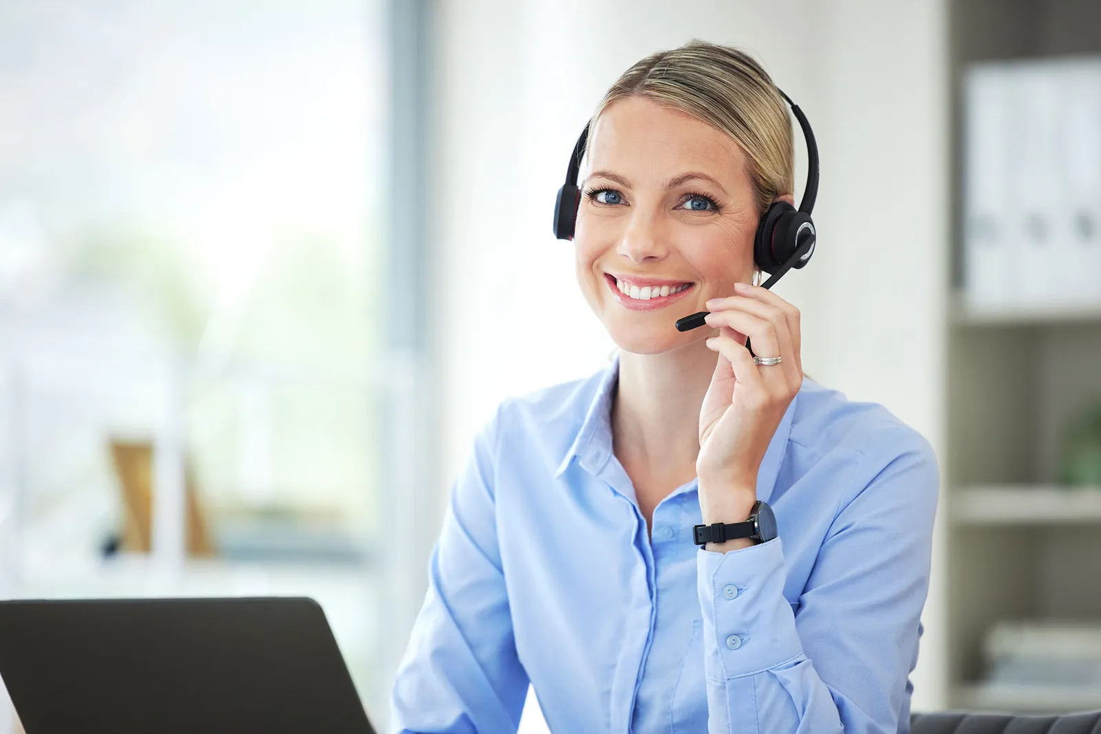 Freundliche Service-Mitarbeiterin mit Headset am Arbeitsplatz